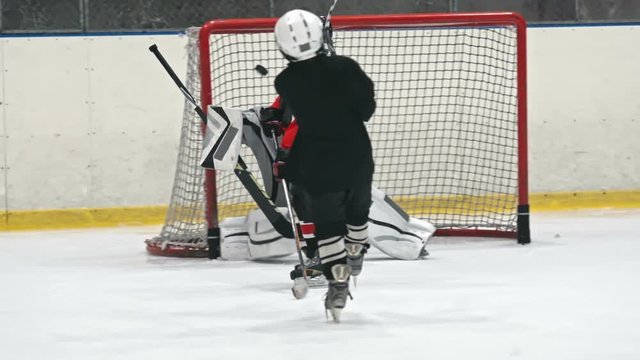 Little hockey player scoring goal into the net of opponent in slow motion