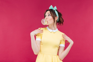 Thoughtful attractive young woman blowing bubble from chewing gum