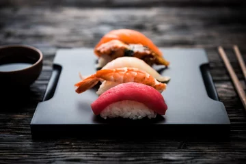 Foto op Plexiglas sashimi sushi set met soja op zwarte achtergrond © Ievgen Skrypko