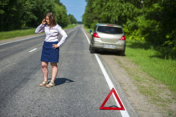 Broken car on the roadside and woman with phone