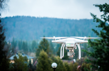 white quadrocopter with camera in mountains and beautiful landscape on the background
