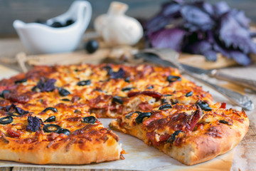 Appetizing pizza with salami, black olives and cheese close up.