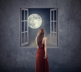 Beautiful woman in red dress walking to opened window with moon