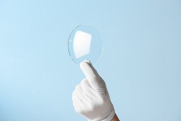 New features glass or plastic research, hand in glove holding circle piece of transparent material