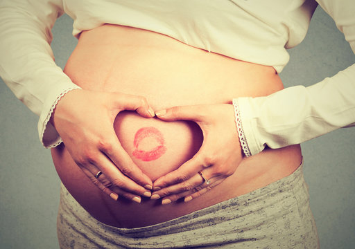 Closeup of a pregnant belly with lipstick sign