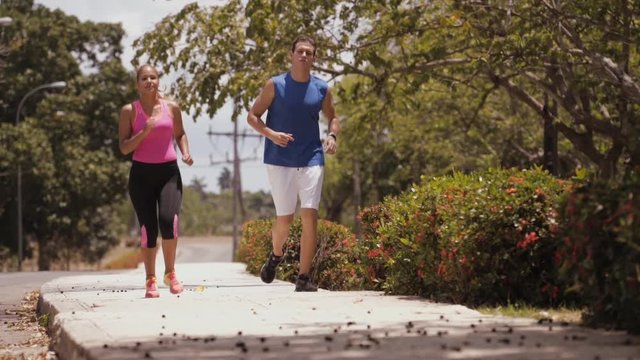 Young people doing sports activity, girl and friend running, man and woman jogging on the street, happy friends and hispanic couple. Leisure, recreation, fitness, exercise, training. Slowmotion