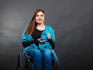 Woman invalid girl on wheelchair holds tea mug