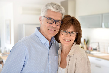 Portrait of happy senior couple standing in kitchen