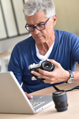 Senior man uploading pictures on laptop