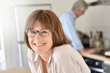 Portrait of smiling senior woman, husband in background