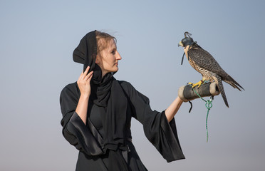 a woman in emirati dress (abaya) with a falcon