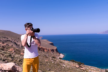 man taking a picture of the landscape against the sea 