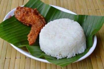 deep fried chicken wing eat couple with plain rice on fresh banana leaf
