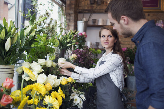 Florist Serving Male Customer With Roses In Shop