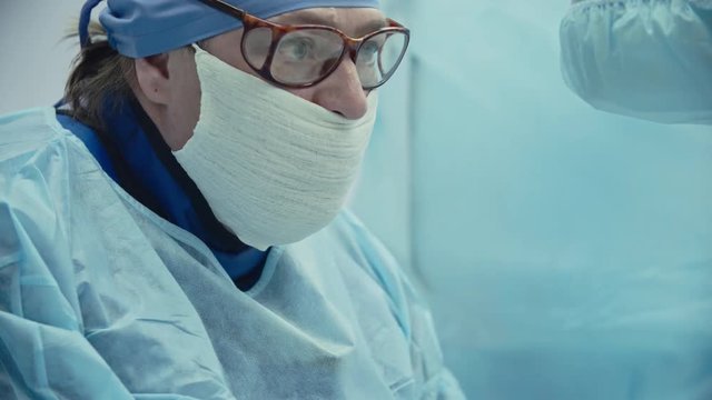 Close-up of experienced female doctor in glasses performing surgery, shot on Sony NEX 700 + Odyssey 7Q