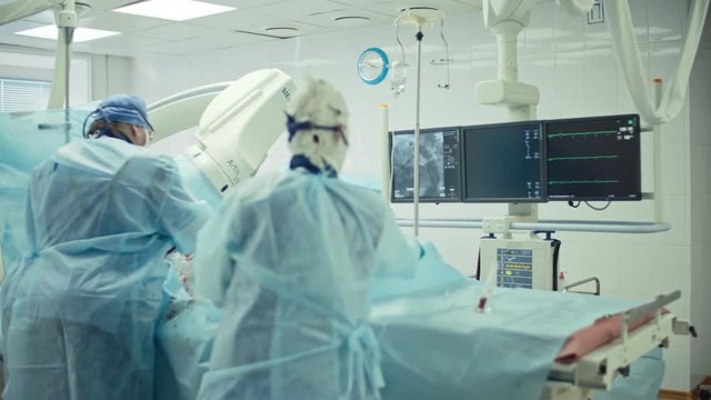 Female surgeon looking at monitors while performing coronary artery bypass surgery assisted by nurse in modern operating room, shot on Sony NEX 700 + Odyssey 7Q