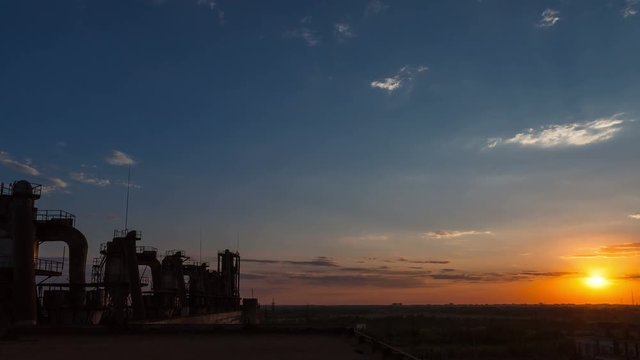 Time lapse. Factory at sunset. Pipeline. Blue sky. Moving clouds.