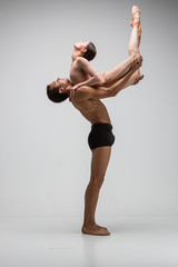 Couple of ballet dancers posing over gray background
