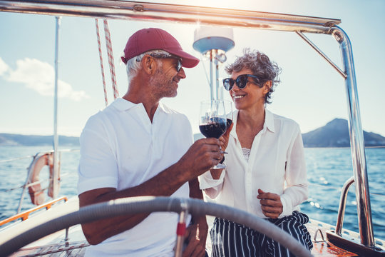 Mature couple toasting with red wine on yacht