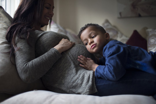 Boy Listening To Pregnant Mother's Stomach At Home