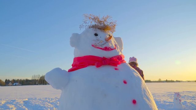The big pink snowman with pink bow tie on his neck twigs on his head and painted pink dots on his body