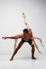 Couple of ballet dancers posing over gray background