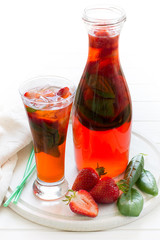 Strawberry lemonade with fresh basil on white wooden background