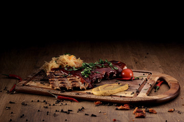 Port steak with red sauce with braised cabbage, fresh cherry tometoes and mustard served on wooden board on rustic wooden counter