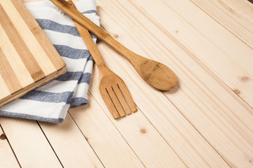 Wooden spoons and other cooking tools with blue napkins on the kitchen table.