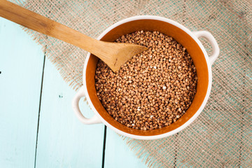 Buckwheat groats in a bowl and wooden scoop