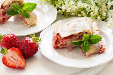 Homemade strudel with strawberries decorated mint leaves  on white wooden background