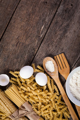 Fototapeta na wymiar Pasta spaghetti with flour, egg on old wooden background