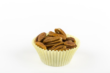 Pecans in a muffin cup on a white background