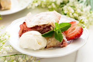 Homemade strudel with strawberries decorated ice-cream and mint leaves  on white wooden background