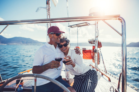Mature couple toasting with red wine on yacht