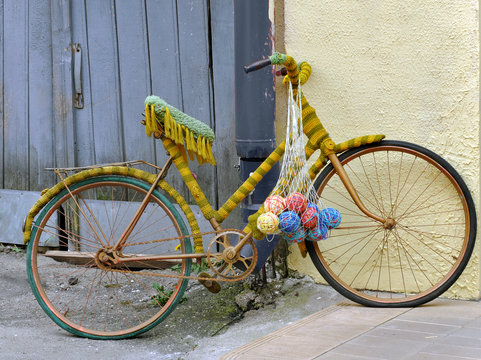 Vintage bicycle tied with thread and balls of woolen thread. The yard of the shop crafts, Grodno, Belarus.