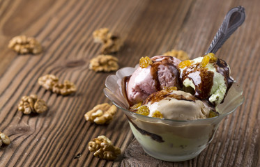 Different ice creams in a glass bowl with nuts and raisins