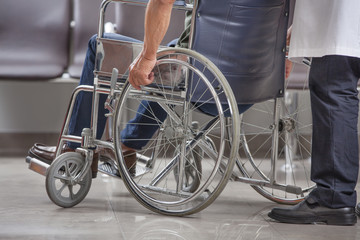 man's arm pushing wheel of wheelchair