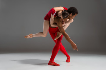 Couple of ballet dancers posing over gray background