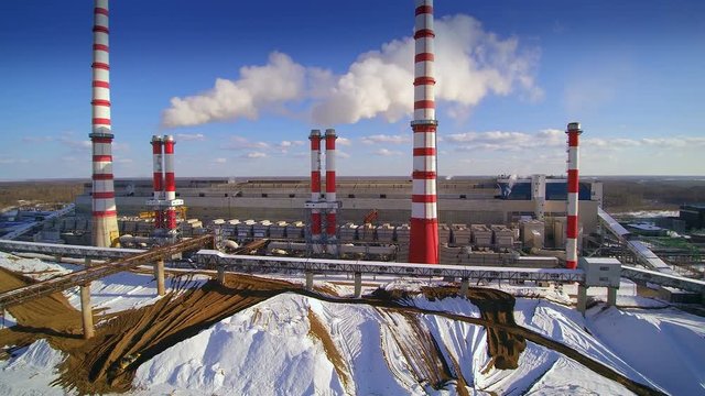The view of the power plant in the city. Electricity is produced at a an electric power plant. Some fuel source such as coal oil natural gas or nuclear energy produces heat.