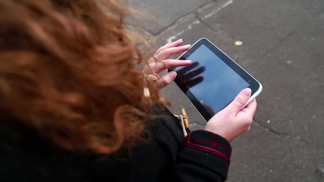 Girl is Walking and Using a Tablet
