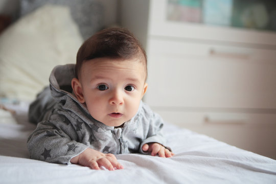 Small baby crawling on the bed in white room.On his face interes