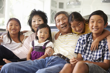 Portrait Of Grandparents With Grandchildren Sitting On Sofa
