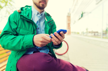 close up of man with smartphone sitting on bench