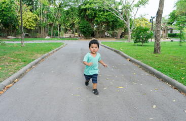 Little Boy running in a park or garden among trees