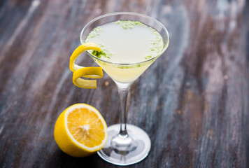 Yellow martini cocktail with lemon and mint on the rustic wooden background. Shallow depth of field.