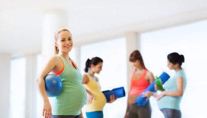 happy pregnant woman with ball in gym