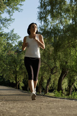 Fototapeta na wymiar Sporty young woman listening to music while running outdoors