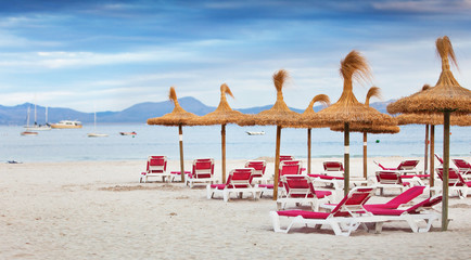 the beach with sunbeds and parasols of straw