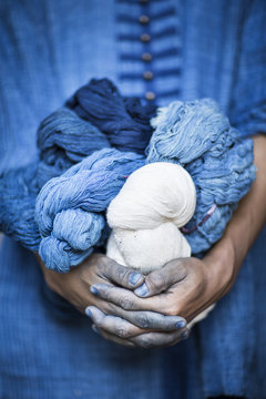 A man holding balls of wool dyed with natural indigo color